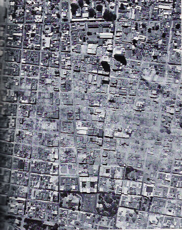 Low-resolution black-and-white vertical aerial photograph of a regular city street grid in central Managua, blocks and building footprints visible from above.