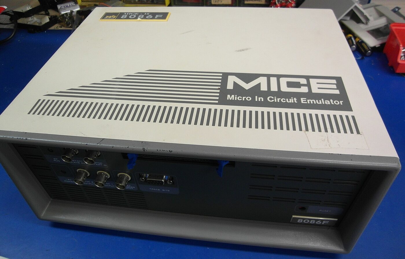A beige and grey benchtop instrument on a workbench, its lid marked MICE Micro In Circuit Emulator, with BNC and D-sub sockets on the front panel.