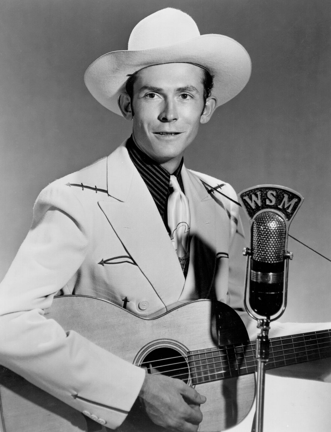 Black-and-white publicity photograph of country singer Hank Williams in a light-coloured western suit and hat.