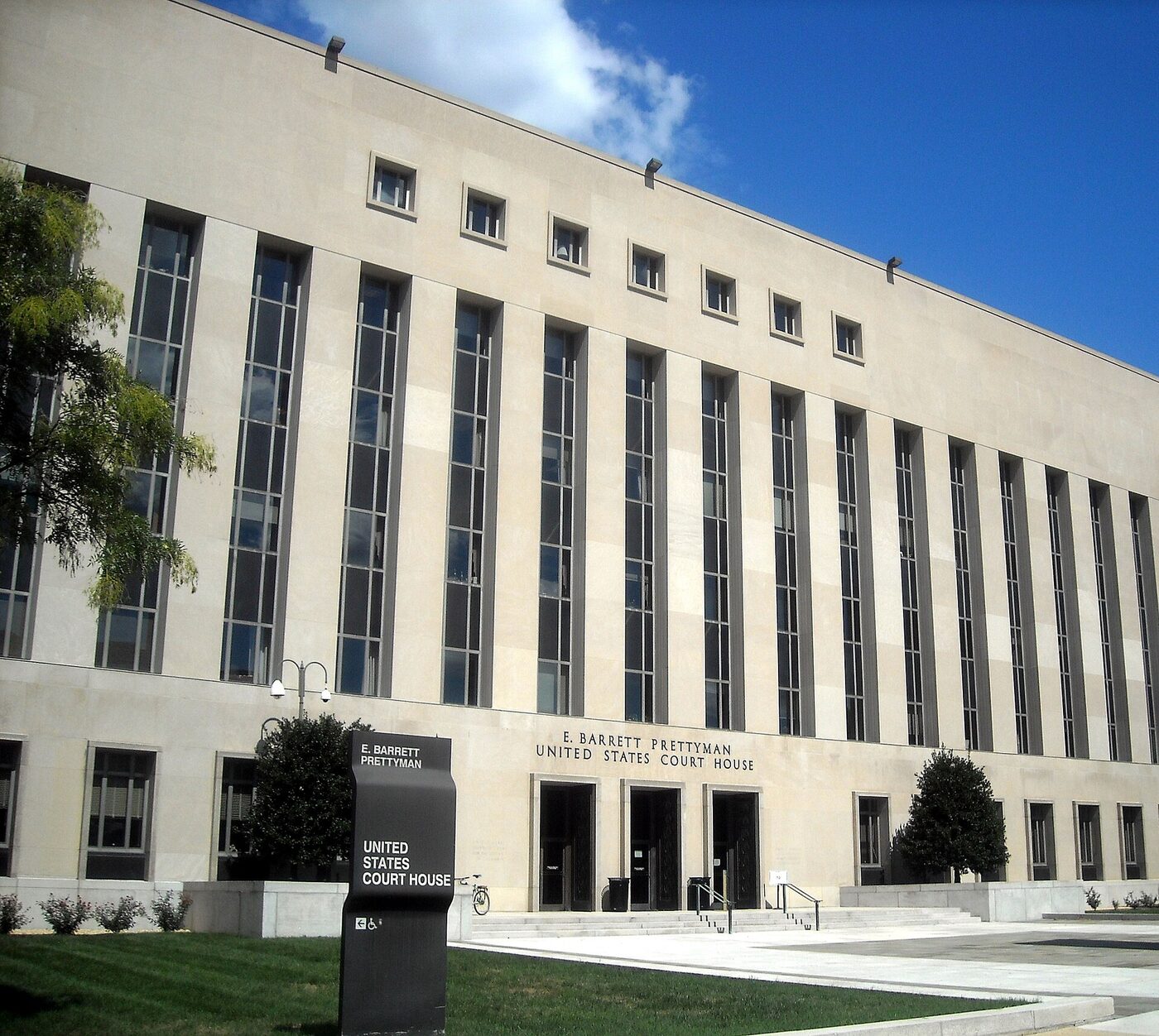 A mid-century stone federal courthouse seen from across a street, with regular rows of windows and trees in front.