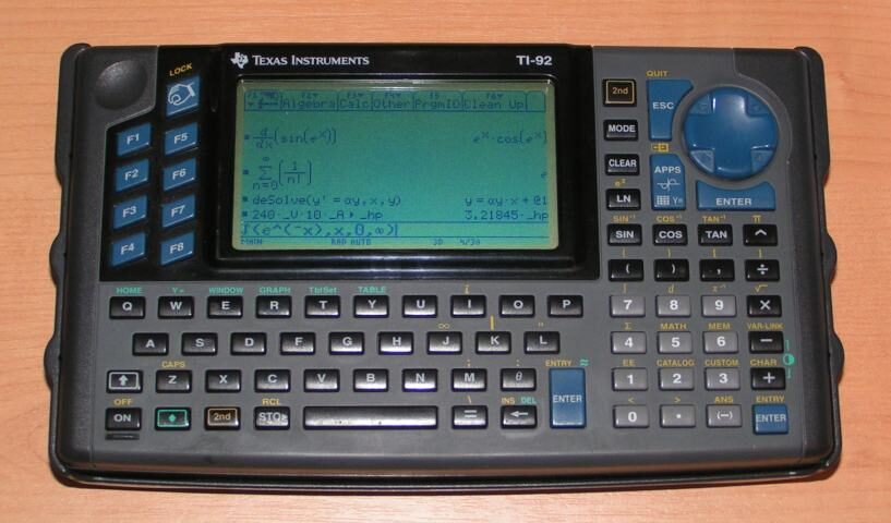 A dark grey handheld Texas Instruments TI-92 calculator with a QWERTY keyboard, its wide monochrome screen showing symbolic calculus expressions.