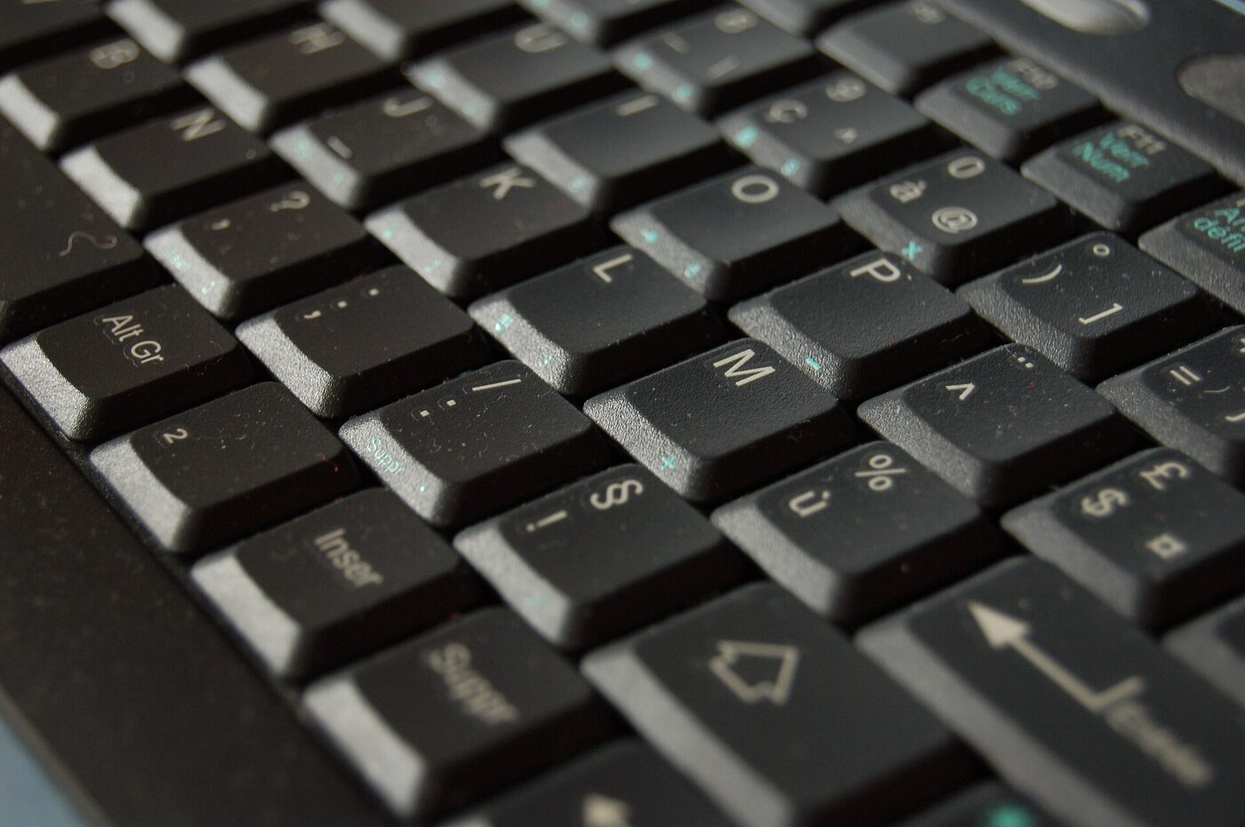 Close-up photograph of the right-hand keys of a black French AZERTY laptop keyboard, with the AltGr key at the left, the à and at-sign key and the ù and percent key visible, and small third-level symbols printed at the lower right of several keycaps.