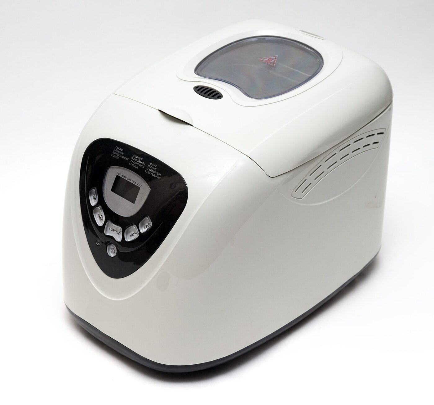 A white countertop bread machine with a hinged lid, a viewing window and a black control panel carrying an LCD display, a numbered programme list and small buttons.