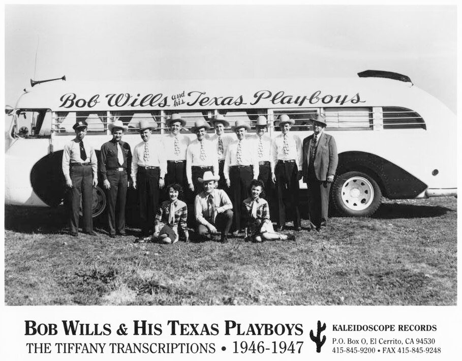 Black-and-white publicity photograph of Bob Wills and his Texas Playboys, in matching western outfits, posed in front of a tour bus lettered with the band's name.