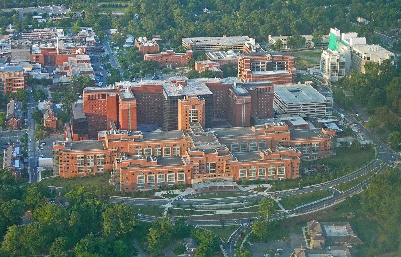 Aerial photograph of a large campus of red-brick research and hospital buildings surrounded by trees and roads.