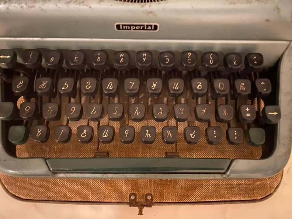Close-up of a typewriter keyboard, the maker's badge reading Imperial, with each black keycap bearing a character of the Osmanya script instead of a Latin letter.