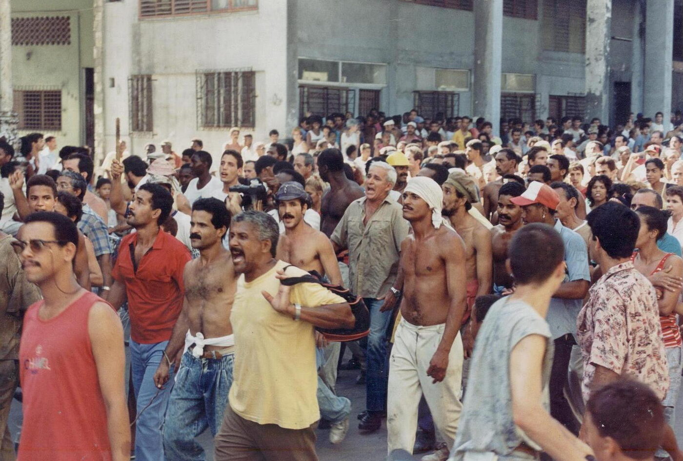 Black-and-white-toned street photograph of a dense crowd of people filling a road in Havana during the August 1994 protest.