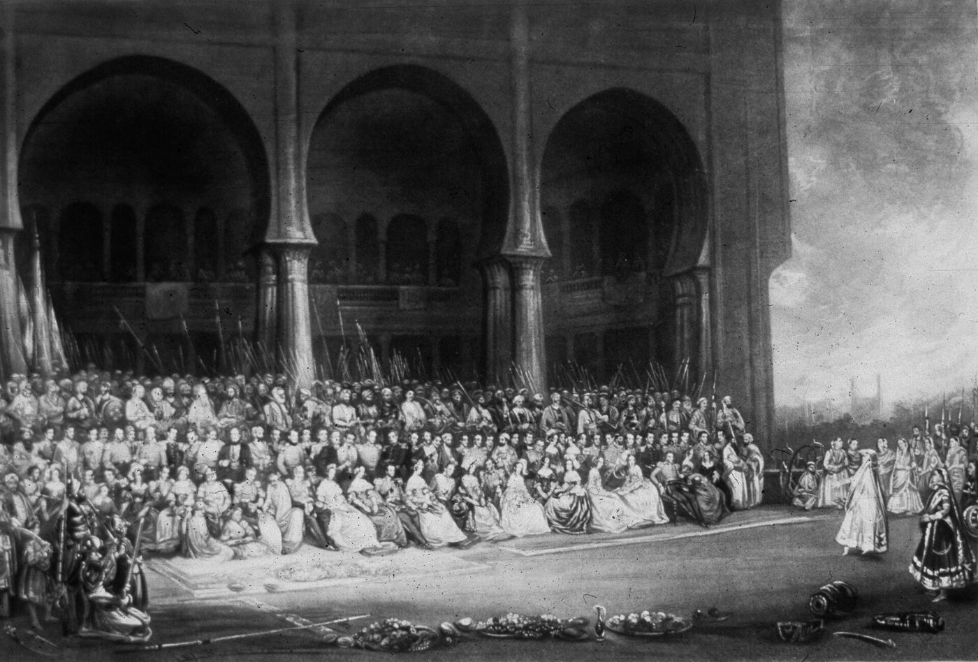 Nineteenth-century painting of a crowded gathering seated on carpets before an arcade of tall arches, with standing performers and attendants at the right and dishes set out in the foreground.